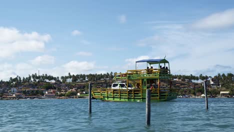 A-large-transportation-ship,-with-tourists-and-cars,-sailing-towards-the-tropical-coastal-town-of-Barra-do-Cunhaú-in-Rio-Grande-do-Norte,-Brazil-from-the-tropical-Restinga-beach-on-a-sunny-summer-day