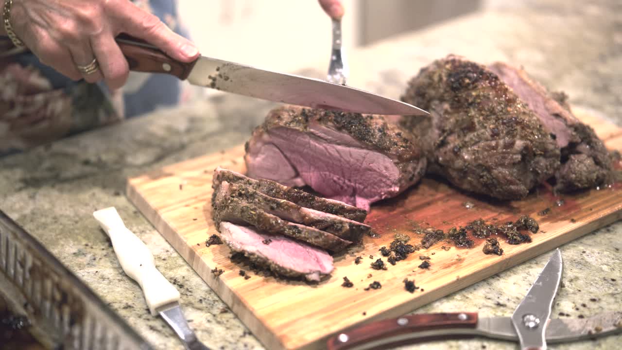 en una cocina luminosa en navidad, una mujer alegremente tallada suculento cordero asado en una tabla de corte de bambú, capturando la calidez de la tradición festiva