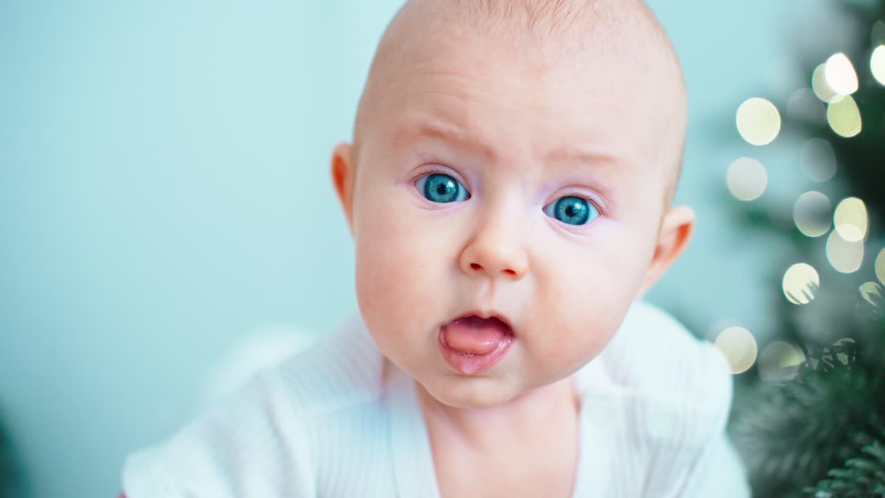 Søt baby med blå øyne rekker ut tungen og ser seg rundt