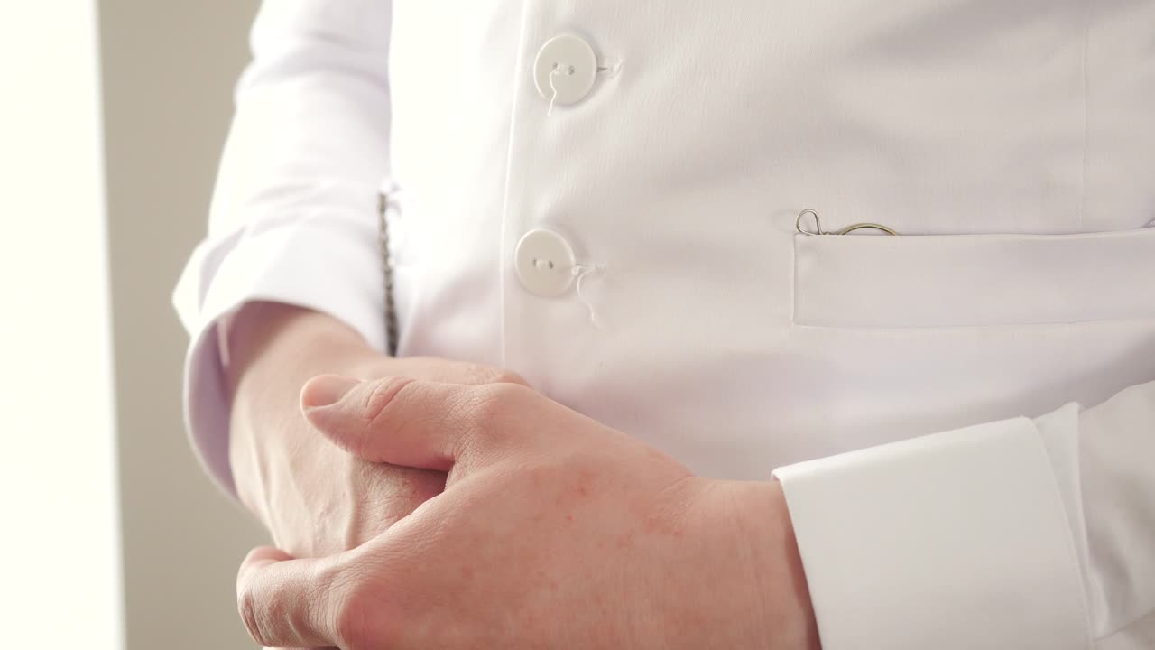 Uomo in abito formale bianco che sistema l'orologio da taschino e gli occhiali