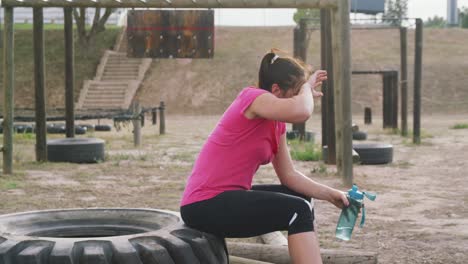 mujer caucásica descansando después de hacer ejercicio en el campamento de entrenamiento