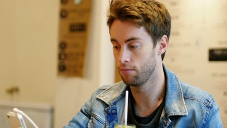 man using mobile phone while drinking juice