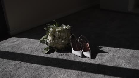 white high-heeled shoes and bridal bouquet in sunlight on a carpeted floor