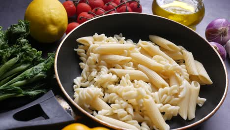 uncooked pasta in a pan with vegetables and ingredients