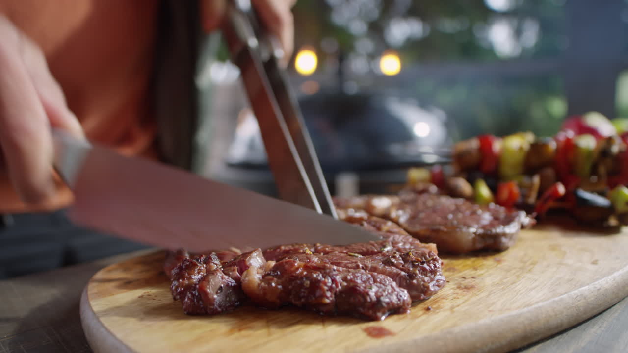 Cutting Hot Beef Steak Cooked on BBQ