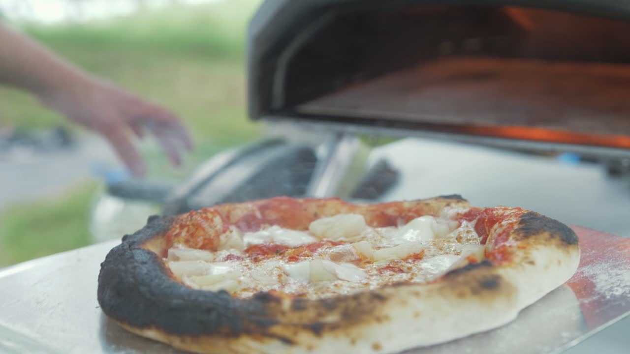 야외 오븐에서 새로 구운 피자를 제거하는 것