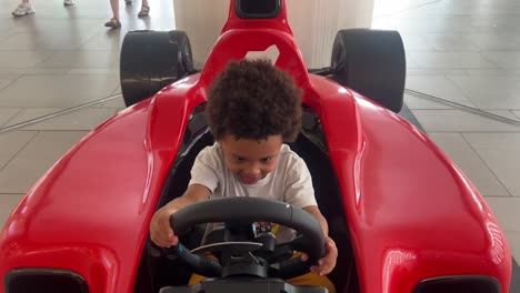 Niño-Afro-Europeo-Disfrutando-Jugando-Con-El-Coche-De-Juguete-Rojo-F1