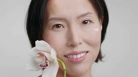 beautiful woman with orchid and facial cream