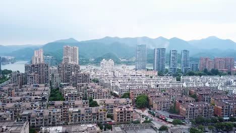 tonglu city skyline, urban scenery, establishment drone shot, aerial ascending movement above neighbourhood apartments, tonglu town during hazy morning, overview in hangzhou, zhejiang province, china