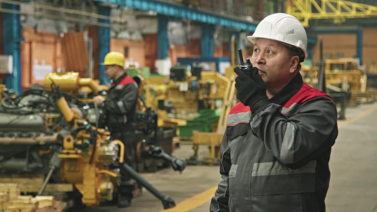 Asian Foreman Talking On Walkie-Talkie At Plant