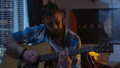 man playing acoustic guitar in bedroom