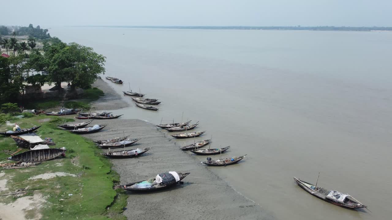 Rows of boats are tied up on the river embankment.