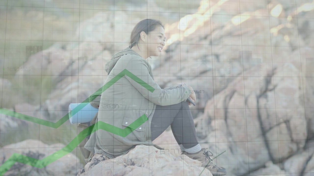 Mulher caminhante sentada em rocha observando grade animada e gráfico de linha verde subindo, mostrando crescimento tecnológico.