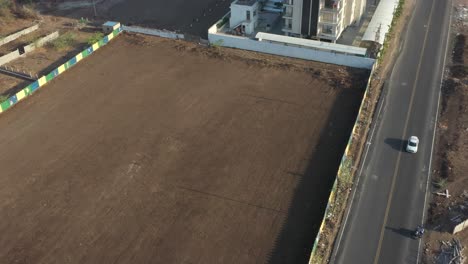 aerial view of an empty land plot, road, and adjacent buildings