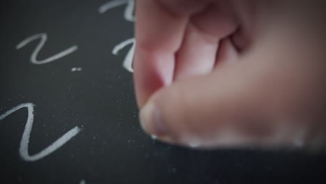 large number of question marks are written in chalk on a blackboard