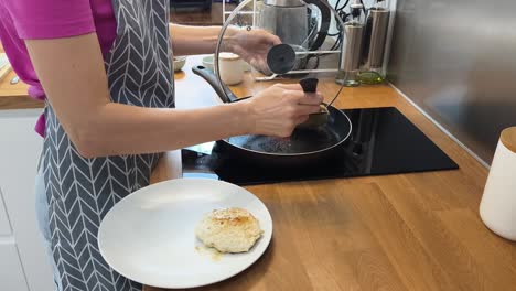 una mujer freyendo una chuleta de carne.