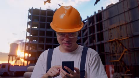 trabajador asiático usando un teléfono inteligente en el sitio de construcción