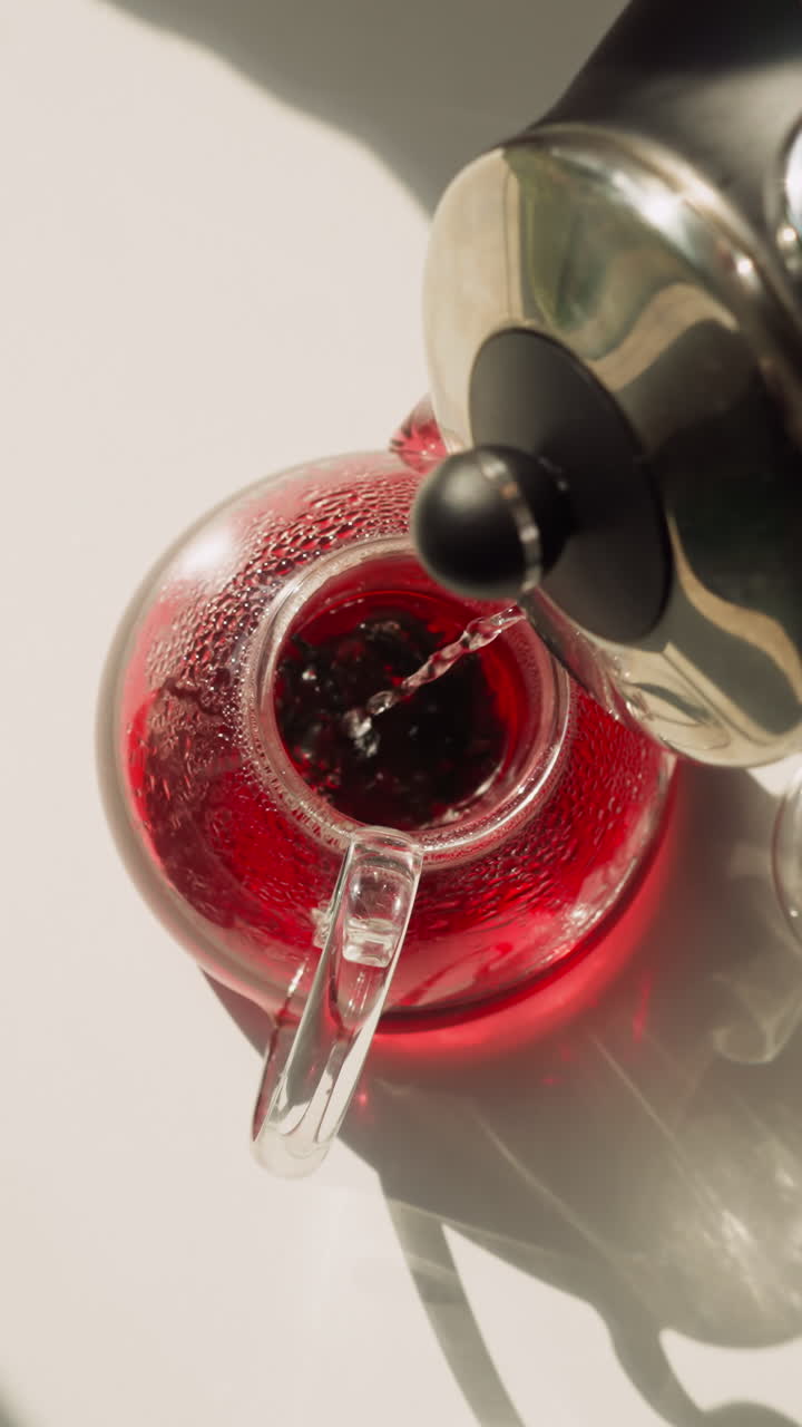 테이블 위에 뜨거운 물로 차 비를 채우기: 부에서 전기 비에서 흐르는 히비스쿠스 차를 양조하는 과정