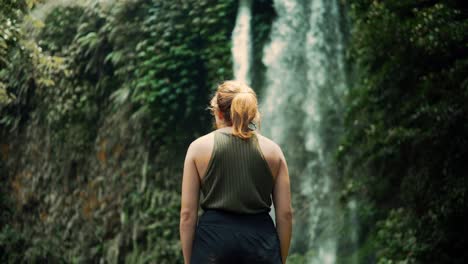 Female-Hiker-Getting-Misted-By-Sendang-Gile-Waterfall-In-Lombok,-Indonesia