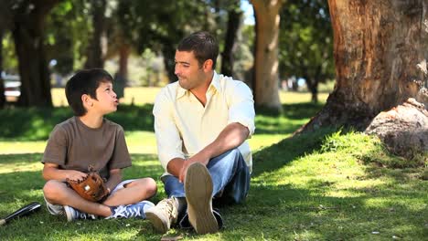 un niño hablando con su padre sentado en el césped
