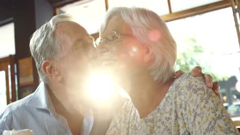 senior man kissing senior woman in cafe 4k