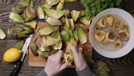 mujer limpiando alcachofas. proceso de cocción en la cocina. primer plano