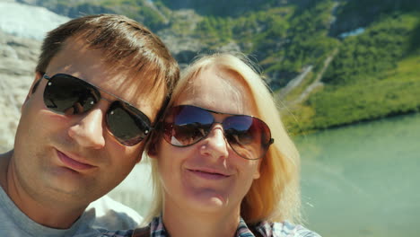 young couple relieves himself on the video on the background of mountains and glacier in norway jour