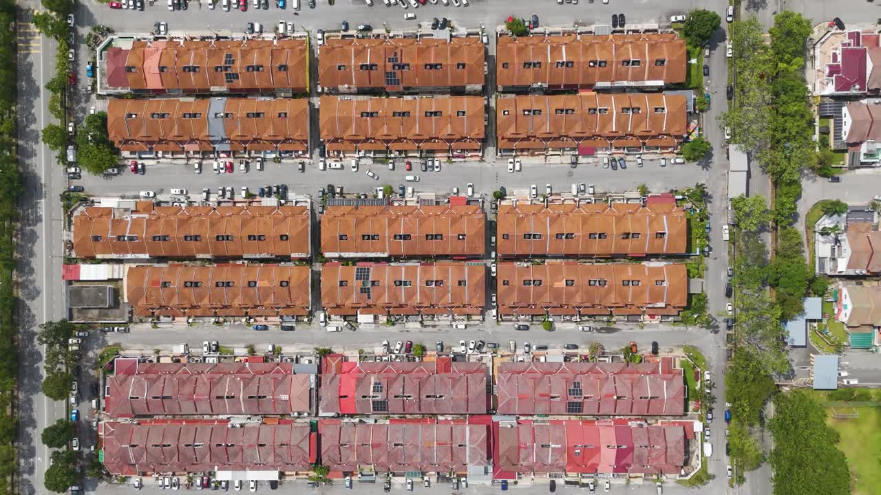 Top-down aerial view of a tightly packed housing area in Klang, Malaysia, showing rows of red rooftops, narrow streets, and parked vehicles in a suburban neighborhood. UHD.