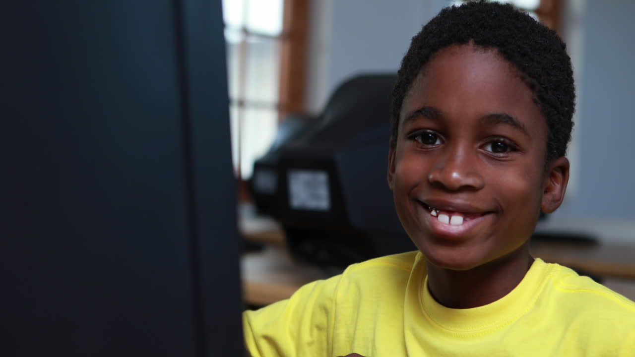 Little boy smiling at camera during computer class