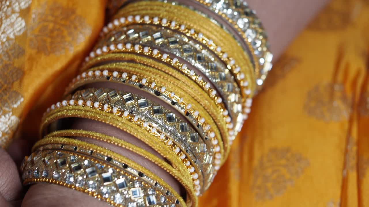 Close-up of traditional gold and embellished Indian bangles on an arm
