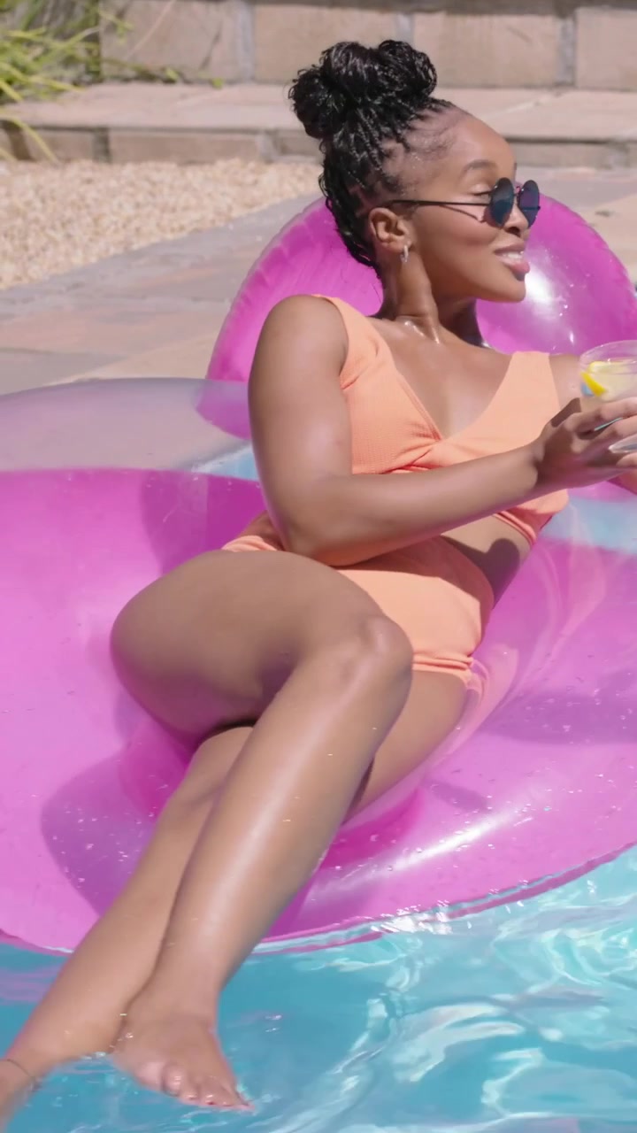 Vertical video: Smiling woman in bikini reaching and toasting glasses with man after laugh at pool
