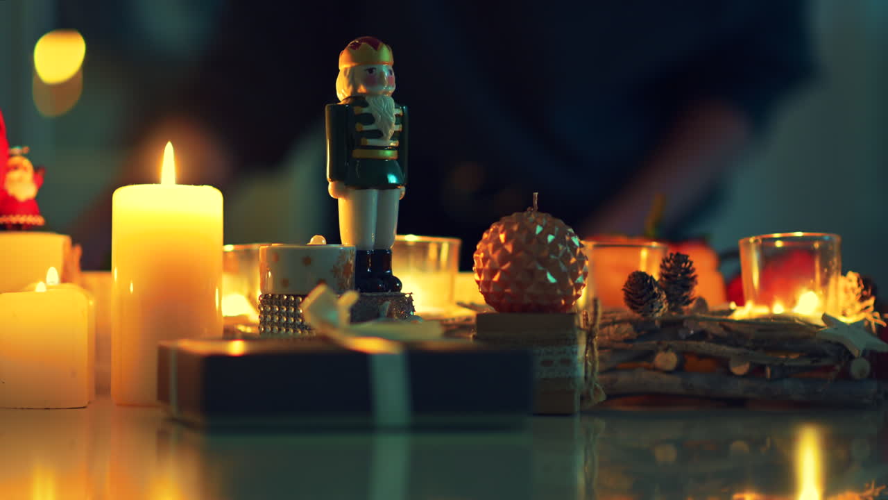 A charming display of holiday decorations features glowing candles, a nutcracker figurine, and twinkling lights, setting a warm and inviting atmosphere for the season