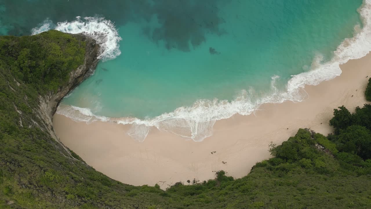 Vista aerea di una scogliera verdeggiante che domina la spiaggia di Kelingking a Nusa Penida.