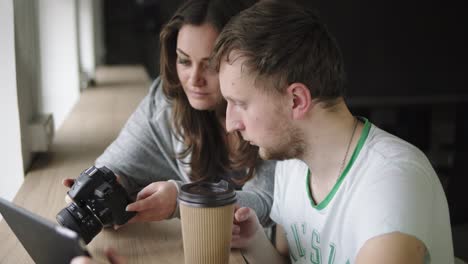 Work-meeting-in-photo-agency.-Client-and-photographer-discuss-the-order-and-watch-the-results-of-work.-Coffee-cup-at-the-table.-Shot-in-4k