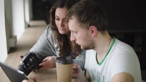 work meeting in photo agency. client and photographer discuss the order and watch the results of work. coffee cup at the table. shot in 4k