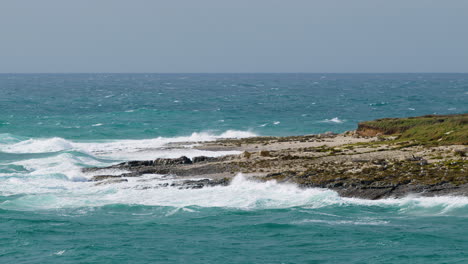 Große-Wellen,-Die-Auf-Der-Insel-Fenoliga-Mit-Möwen-Bei-Bewölktem,-Stürmischem-Wetter-Zermalmen