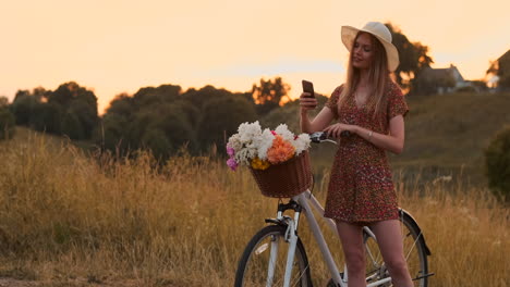 Ziemlich-Süßes-Mädchen,-Das-An-Einem-Sonnigen-Tag-Im-Park-Mit-Palmen-Neben-Ihrem-Fahrrad-Ein-Smartphone-Benutzt.-Hübsches-Mädchen,-Das-An-Einem-Sonnigen-Tag-Im-Park-Neben-Ihrem-Fahrrad-Ein-Smartphone-Benutzt.