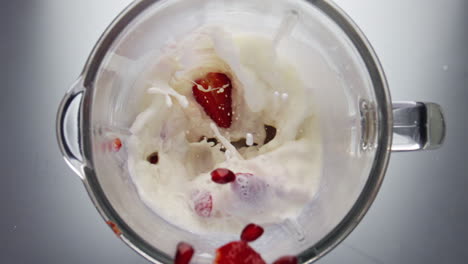 berries falling blending milk in mixer close up. strawberry blueberry mixing.