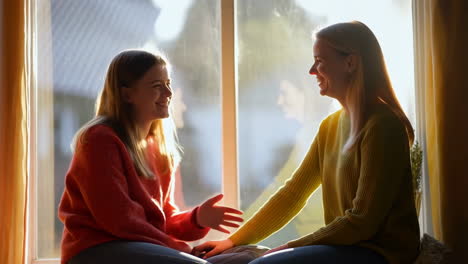 two women talking by a window