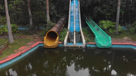 Reveal-shot-of-old-abandoned-waterslides-at-Abandoned-Waterpark-Hue-Vietnam,-aerial