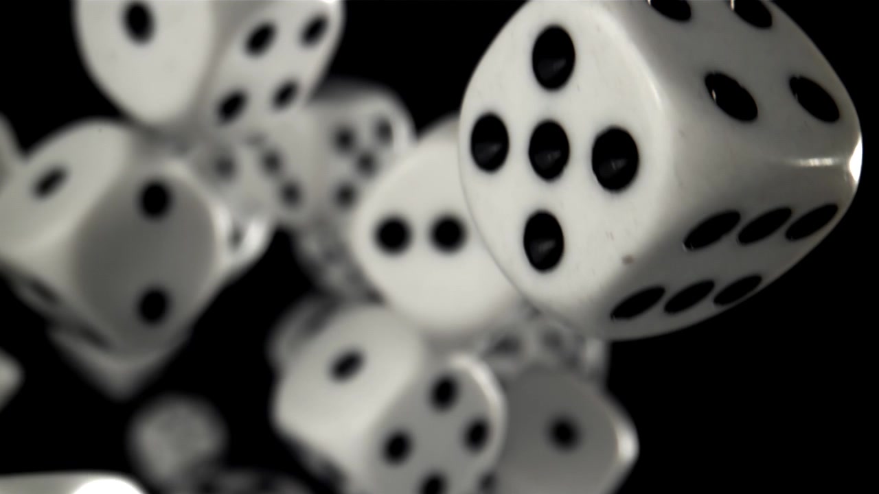Hvide terninger, der falder i slowmotion mod en sort baggrund.