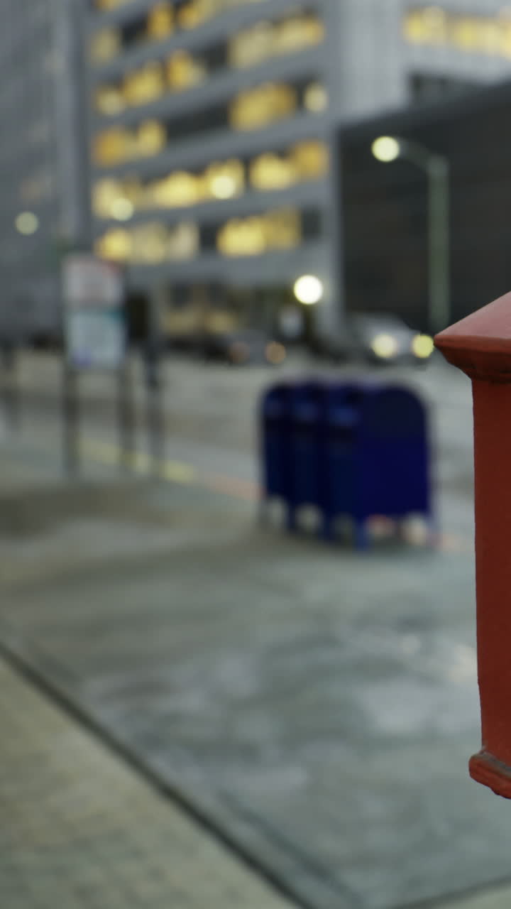 La pioggia cade su una strada cittadina con una cassetta delle lettere in primo piano in una zona trafficata