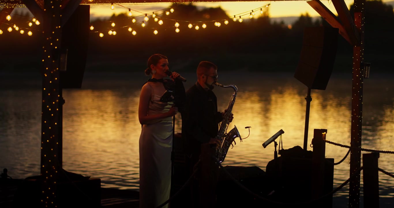 Duo musiziert auf einem Steg bei Sonnenuntergang