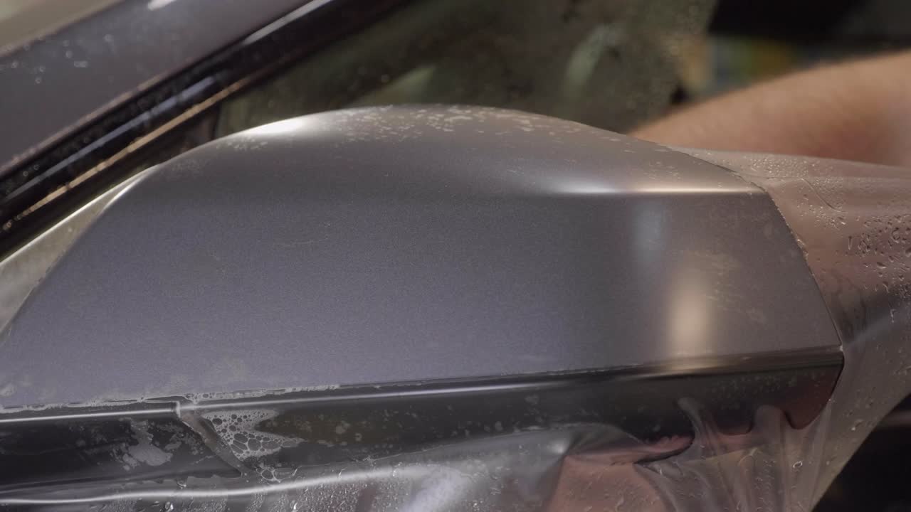 백미러 위로 비닐 호일 조각을 늘이는 자동차 포장지