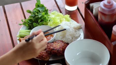 person assembling and eating vietnamese bun cha