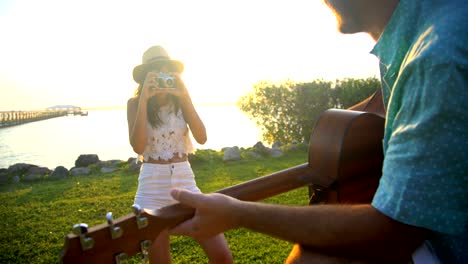 hispanic female taking picture caucasian male playing guitar