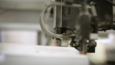 close up of one part of a printing machine, pressing down on paper pile and separating one sheet of paper from another