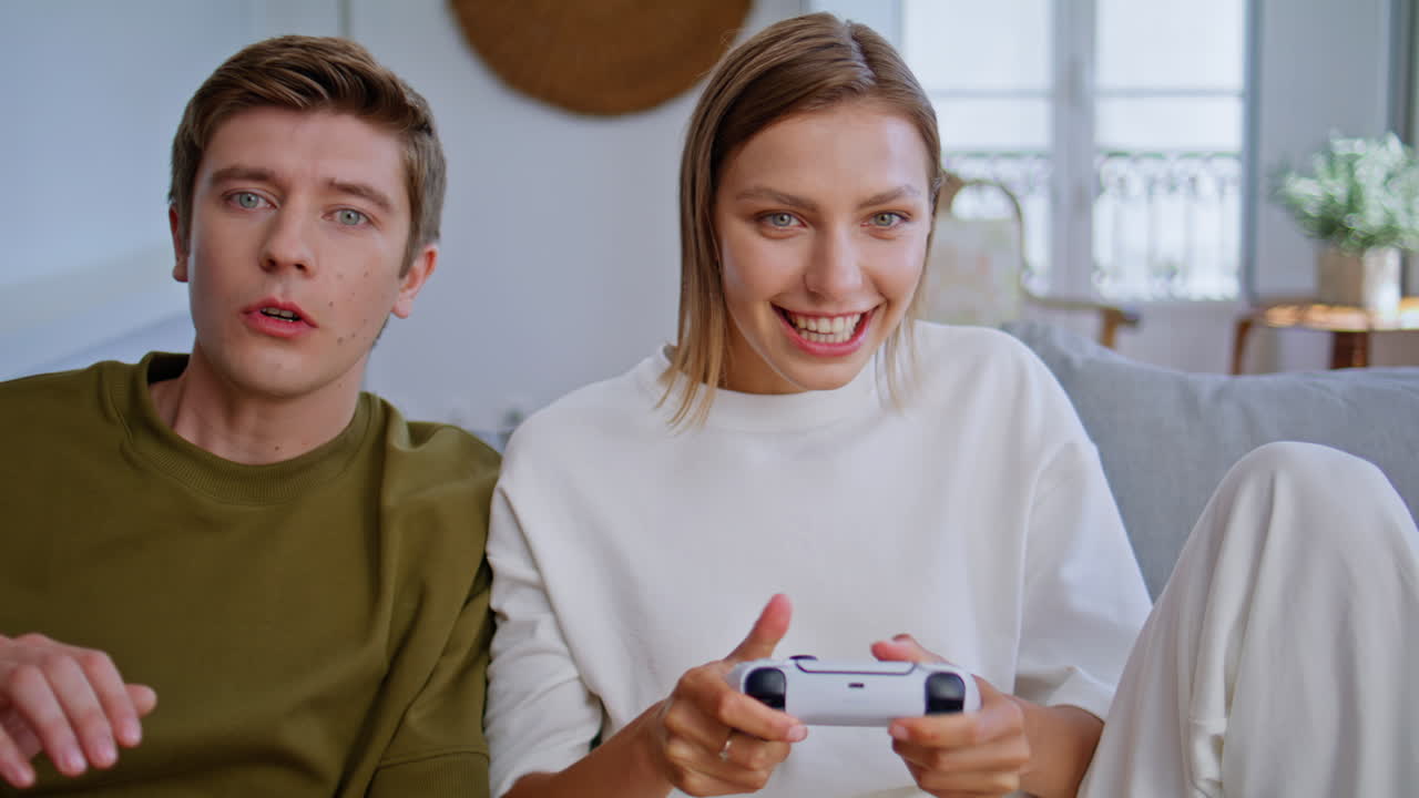 Video gaming couple together sitting apartment sofa closeup. Woman rejoicing win