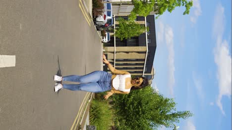 cool-vibe-girl-woman-in-the-middle-of-the-street-fixing-touching-hair-tight-jeans-performing-afro-dance-moves-steps-basic-no-effort-simple-movement-with-style-vertical-view-standing-on-the-road-sunny