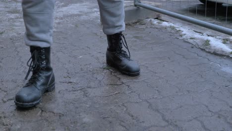 hombre camina por el camino nevado y limpia las botas pisando